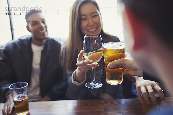 Freunde feiern  rösten Bier und Wein bei Tisch in der Bar