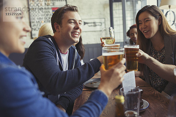 Freunde beim Feiern  Trinken von Bier und Weingläsern am Tisch in der Bar