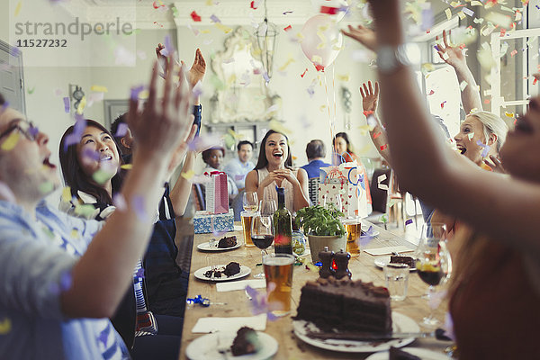 Freunde feiern Geburtstag und werfen Konfetti am Restauranttisch.