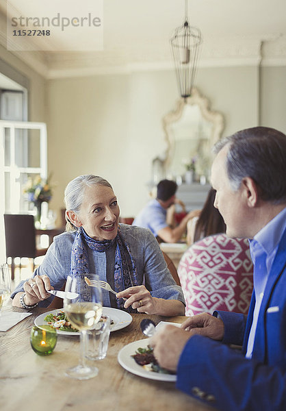 Seniorenpaar beim Reden und Essen am Restauranttisch