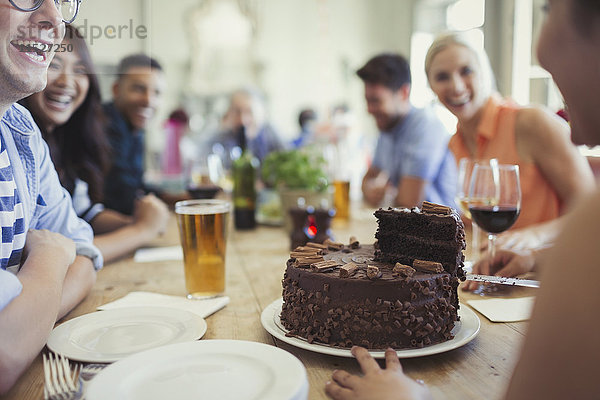 Frau serviert Schokolade Geburtstagskuchen an Freunde am Restauranttisch