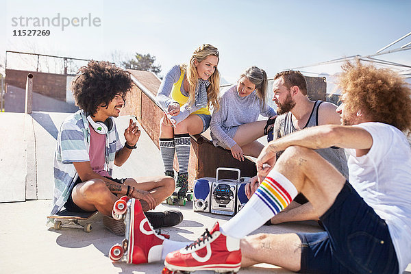 Freunde in Rollschuhen beim Musikhören im sonnigen Skatepark