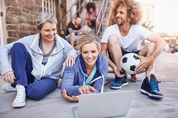 Freunde mit Fußball  die mit dem Laptop rumhängen.