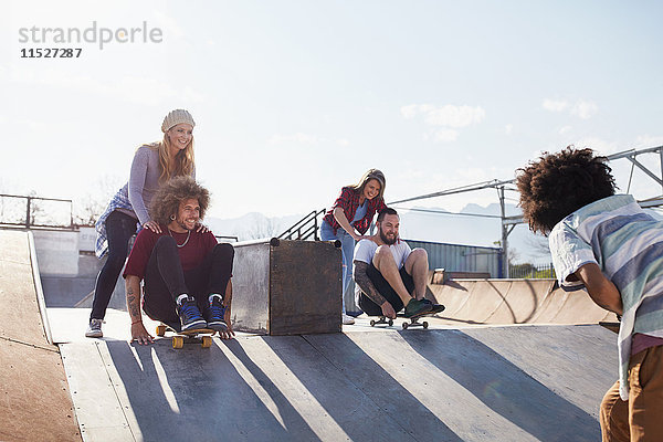 Freunde schieben sich auf Skateboards im sonnigen Skatepark.
