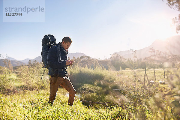 Junger Mann mit Rucksackwanderung  Kontrollkompass im sonnigen  abgelegenen Feld
