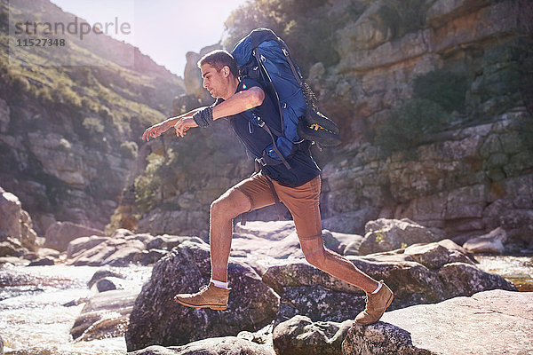 Junger Mann mit Rucksackwanderung  springende Felsen