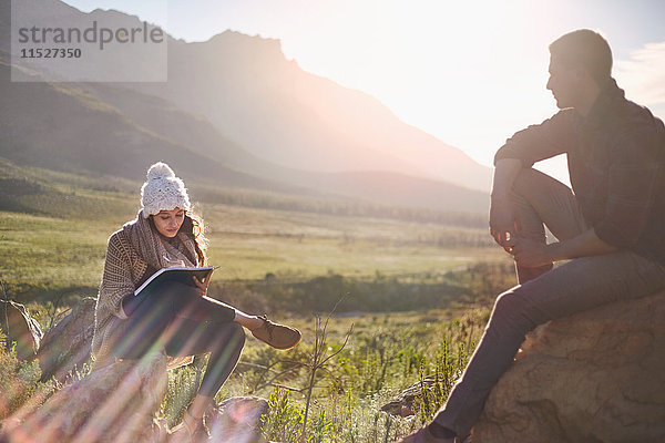 Junges Paar beim Wandern  Ausruhen und Schreiben im sonnigen  abgelegenen Feld