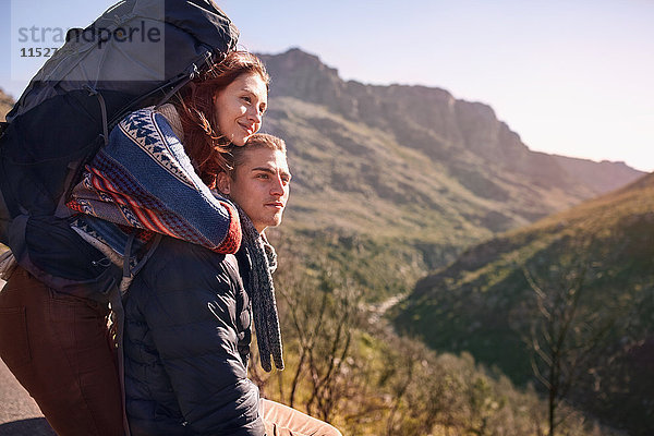 Zärtliches junges Paar mit Rucksackwandern  Pause in sonniger Landschaft