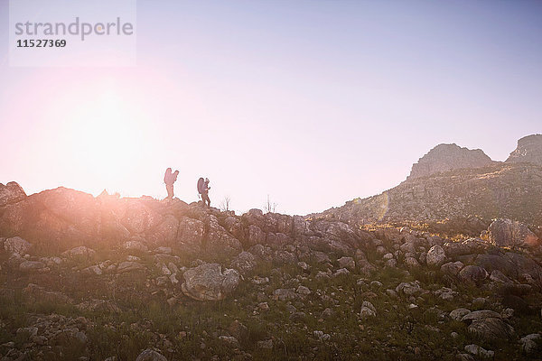 Junges Paar beim Wandern entlang der Felswand unter sonnigem  blauem Himmel