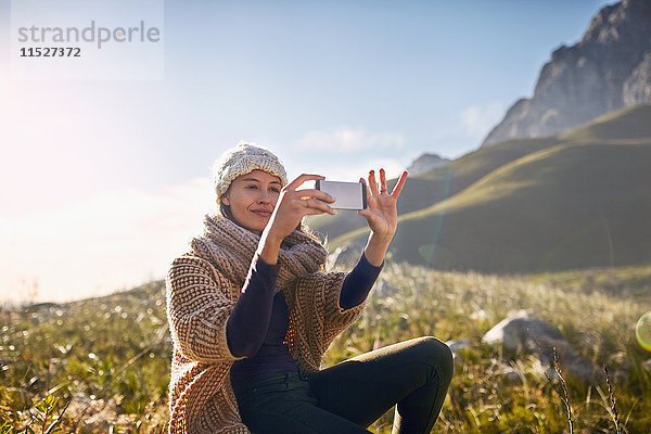 Junge Frau mit Fotohandy im sonnigen  abgelegenen Tal