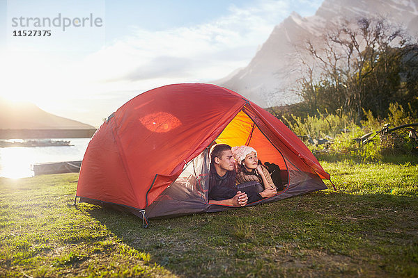 Junges Paar im Zelt auf dem sonnigen Campingplatz am Seeufer