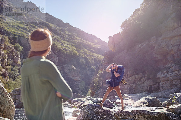 Junge Frau beobachtet Freund beim Wandern  fotografiert zerklüftete Klippen