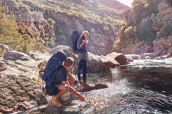Junges Paar mit Rucksäcken beim Wandern  Spritzwasser am Bach