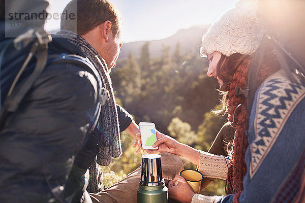 Junge Paare wandern  Kaffeepause machen und Smartphone benutzen