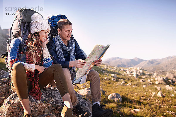 Junges Paar mit Rucksäcken zum Wandern  Ausruhen und Überprüfen der Karte auf sonnigen Felsen