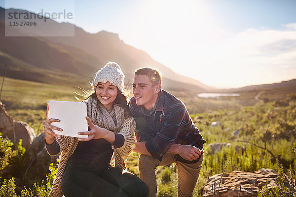 Junges Paar nimmt Selfie mit digitaler Tablettkamera im sonnigen Tal auf