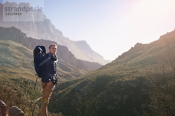 Junger Mann mit Rucksackwanderung  Blick auf den sonnigen Bergblick