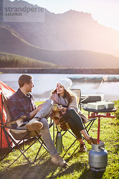 Junges Paar zelten  Kaffee trinken auf dem sonnigen Campingplatz am Seeufer