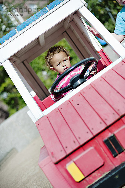 Kleiner Junge im Auto auf dem Spielplatz