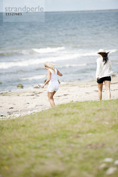 Zwei junge Frauen gehen am Strand spazieren