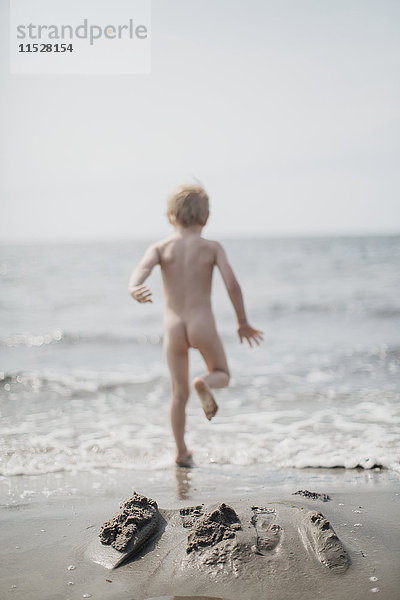 Nackter Junge läuft ins Meer