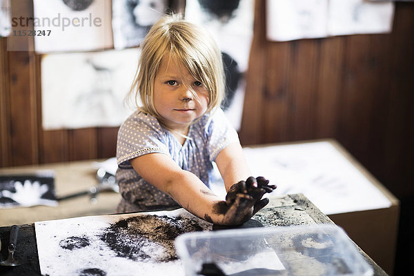 Kleines Mädchen malt mit schwarzer Farbe