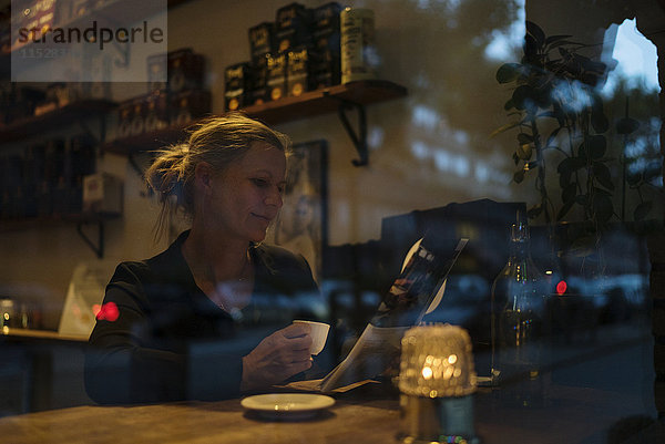 Frau liest Zeitung in einem Cafe