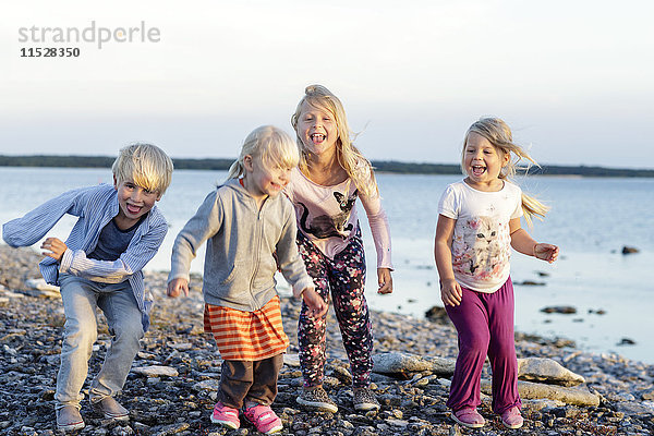 Vier Geschwister spielen am Kieselstrand