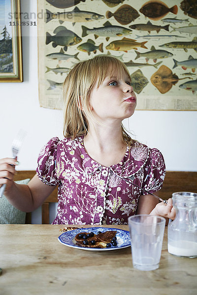 Mädchen isst Pfannkuchen mit Blaubeeren