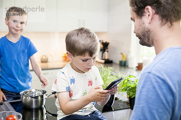 Junge spielt mit Smartphone in der Küche