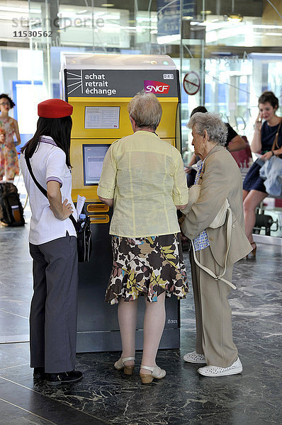 Frankreich  Westfrankreich  Bahnhof von Nantes  Mitarbeiter der SNCF  der älteren Menschen hilft  ihre Fahrkarten am Fahrkartenautomaten in der Abflughalle zu kaufen.