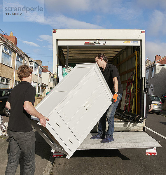 Umzugsunternehmen. Zwei Männer heben eine Garderobe auf den Umzugswagen.