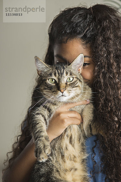 Ein Mädchen kuschelt mit einer Hauskatze.