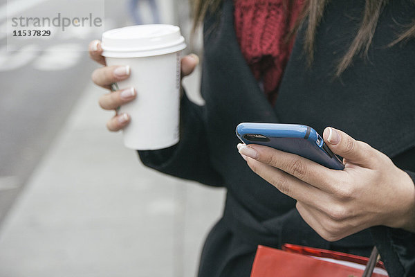Spanien  junge Frau mit Smartphone und Kaffee zum Mitnehmen  Nahaufnahme