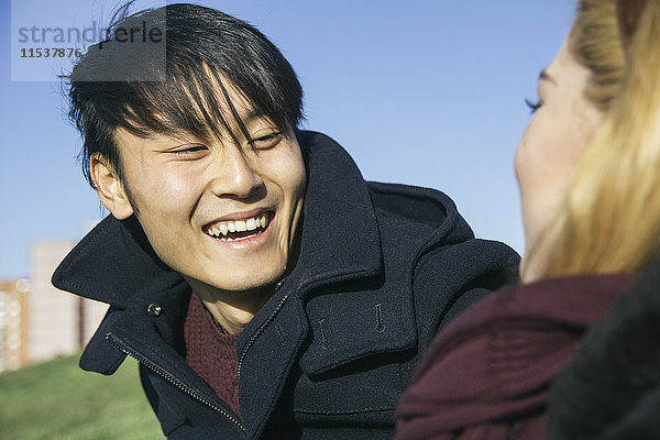 Porträt eines lachenden jungen Mannes von Angesicht zu Angesicht mit seiner Freundin