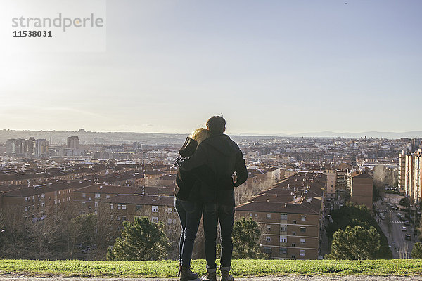 Spanien  Madrid  Rückansicht eines verliebten jungen Paares auf einem Hügel mit Blick auf die Stadt