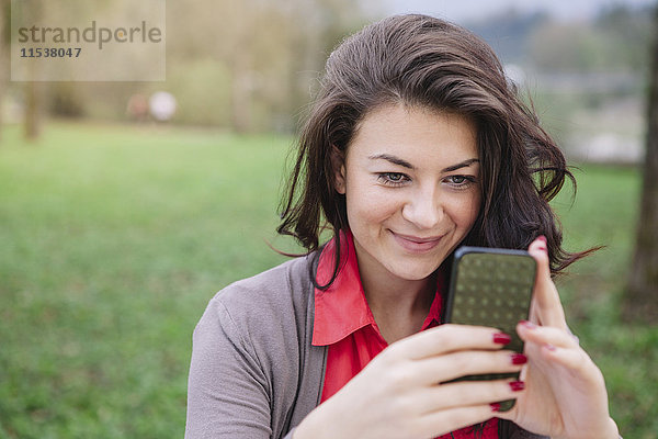 Porträt eines lächelnden jungen Mannes mit Smartphone