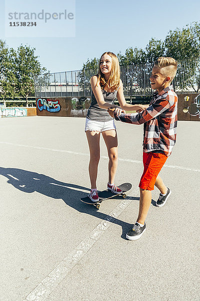 Teenager-Junge unterrichtet seine Freundin beim Skateboarden.