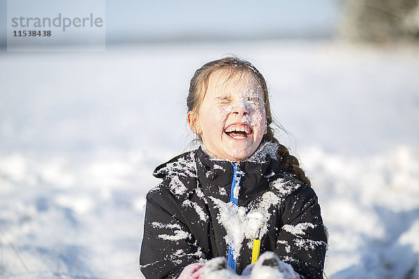 Porträt des lachenden Mädchens mit schneebedecktem Gesicht