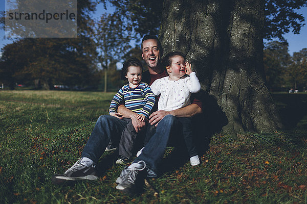Vater und seine Kinder an einem Baum sitzend
