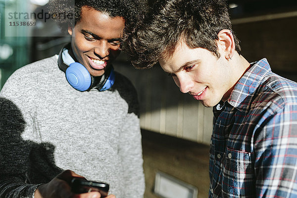 UK  London  zwei junge Männer  die sich die Smartphones anschauen
