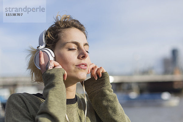 UK  London  Frau hört Musik an der Themse
