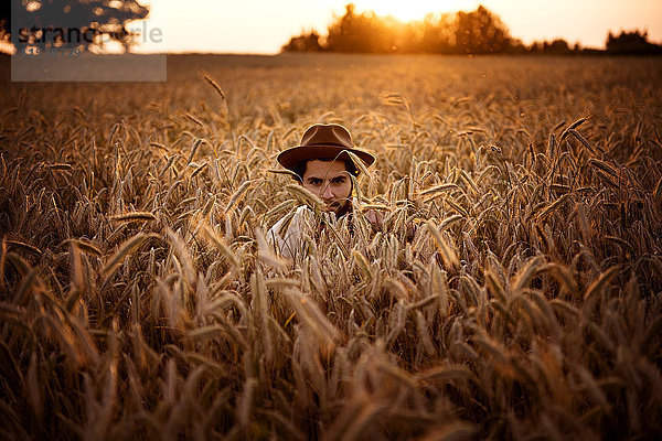 Mann mit Hut versteckt im Maisfeld