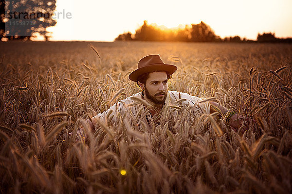 Mann mit Hut versteckt im Maisfeld