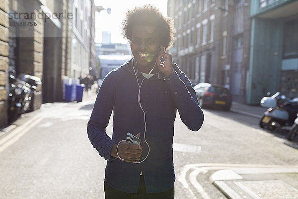 Junger Mann hört Musik vom Handy auf der Stadtstraße