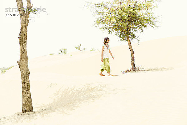 Ein Mann  der allein in der Wüste spazieren geht.