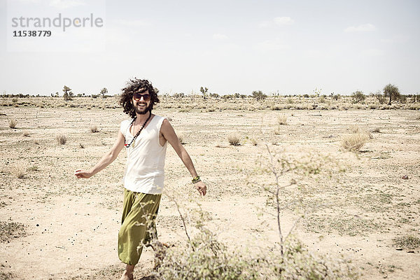 Lächelnder Mann mit Sonnenbrille  der allein in der Wüste unterwegs ist.