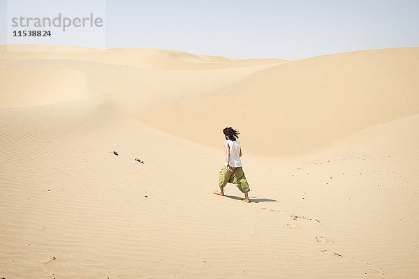 Ein Mann  der allein in der Wüste spazieren geht.