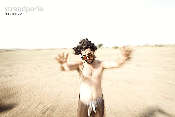 Nackter Mann mit Sonnenbrille in der Wüste