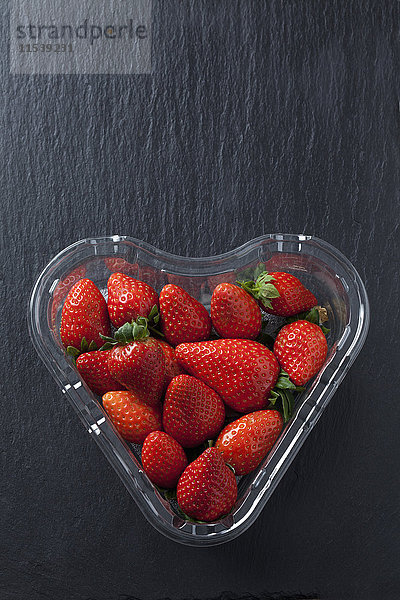 Herzförmige Blisterverpackung mit Erdbeeren auf Schiefer